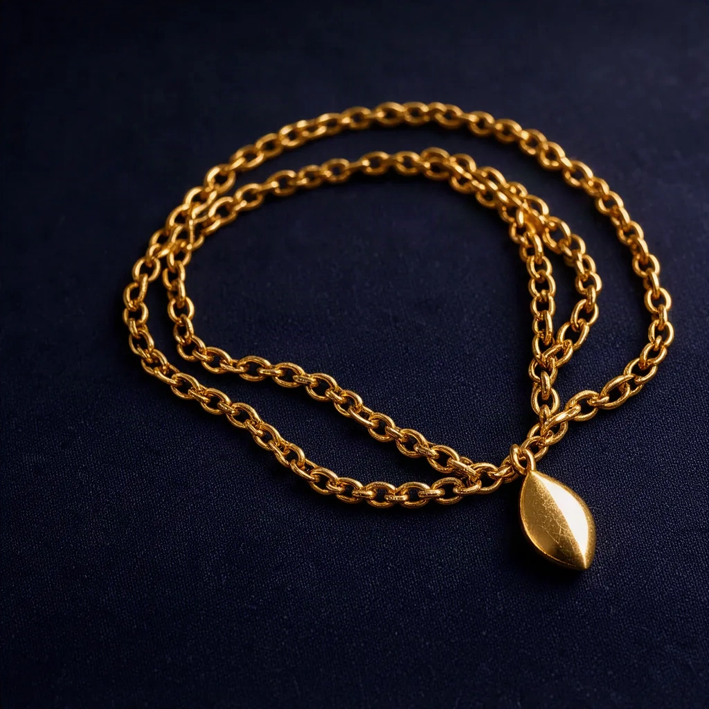 Collier fin doré avec pendentif goutte posé en courbe sur fond nuit